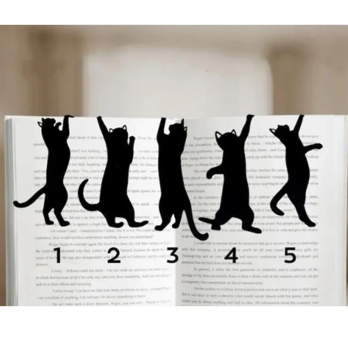The five black metal cat bookmarks in a row on the pages of a book